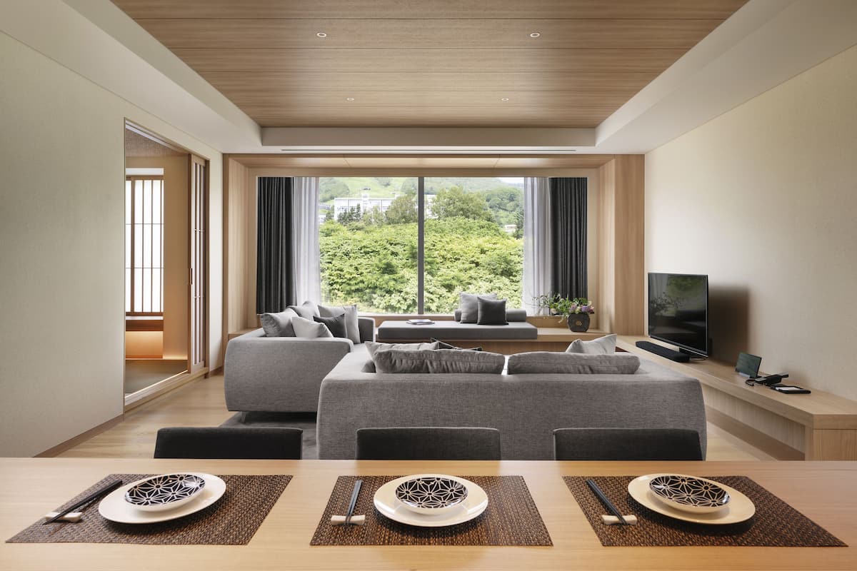 A modern living room with a sofa set, a TV, and a dining table with chopsticks and plates.