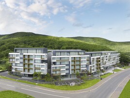 Un hôtel moderne à plusieurs étages, doté d’un toit plat, situé près d’une route et disposant d’un espace de stationnement.