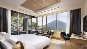 Habitación de hotel moderna con una cama grande, un escritorio y vistas a la montaña.