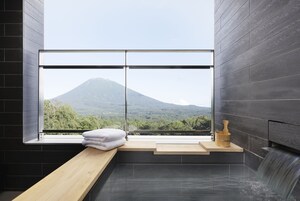 Une salle de bain moderne avec une grande fenêtre, un banc en bois, une baignoire et un seau en bois.