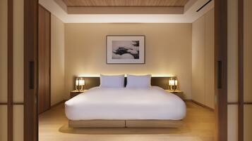 A spacious bedroom with a large bed, wooden flooring, and a framed artwork above the bed.