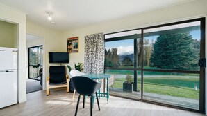 Una sala moderna con comedor, televisor de pantalla plana y un amplio ventanal corredero que da a una vista panorámica al exterior.