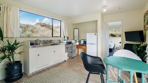Una cocina moderna con un ventanal grande, un lavamanos, un refrigerador y una zona de comedor con mesa y sillas.