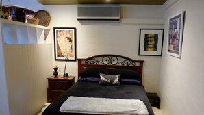 A bedroom with a bed, a nightstand, a chair, and wall-mounted artwork. - Vineyard Accomodation - Self Catering (Henty)