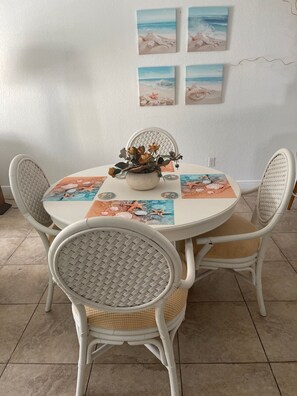 A round dining table with a white tablecloth and a floral centerpiece. Four wicker chairs surround the table. - Bimini Home at the Beach (Bimini)