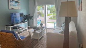 A living room with a television, a ceiling fan, a sofa, a coffee table, and a view of the outdoors. - Bimini Home at the Beach (Bimini)