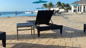 A beachside lounge area with a pool, lounge chairs, and umbrellas. - Bimini Home at the Beach (Bimini)