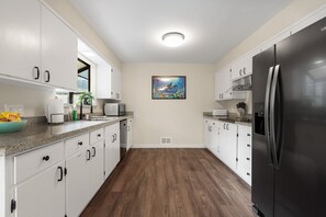 A modern kitchen with white cabinets, a black refrigerator, and a microwave on the counter.