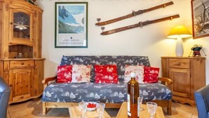 Ein gemütliches Wohnzimmer mit einer Holzsofa, einem Holzschrank und einem Tisch mit Gläsern und einer Flasche.