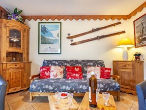 Un salon chaleureux avec un canapé en bois, un meuble en bois et une table sur laquelle se trouvent des verres et une bouteille.