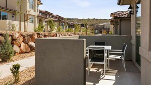 A patio area with a table and chairs, surrounded by a stone wall and small plants. - Libelle Landing by RedAwning (Washington)