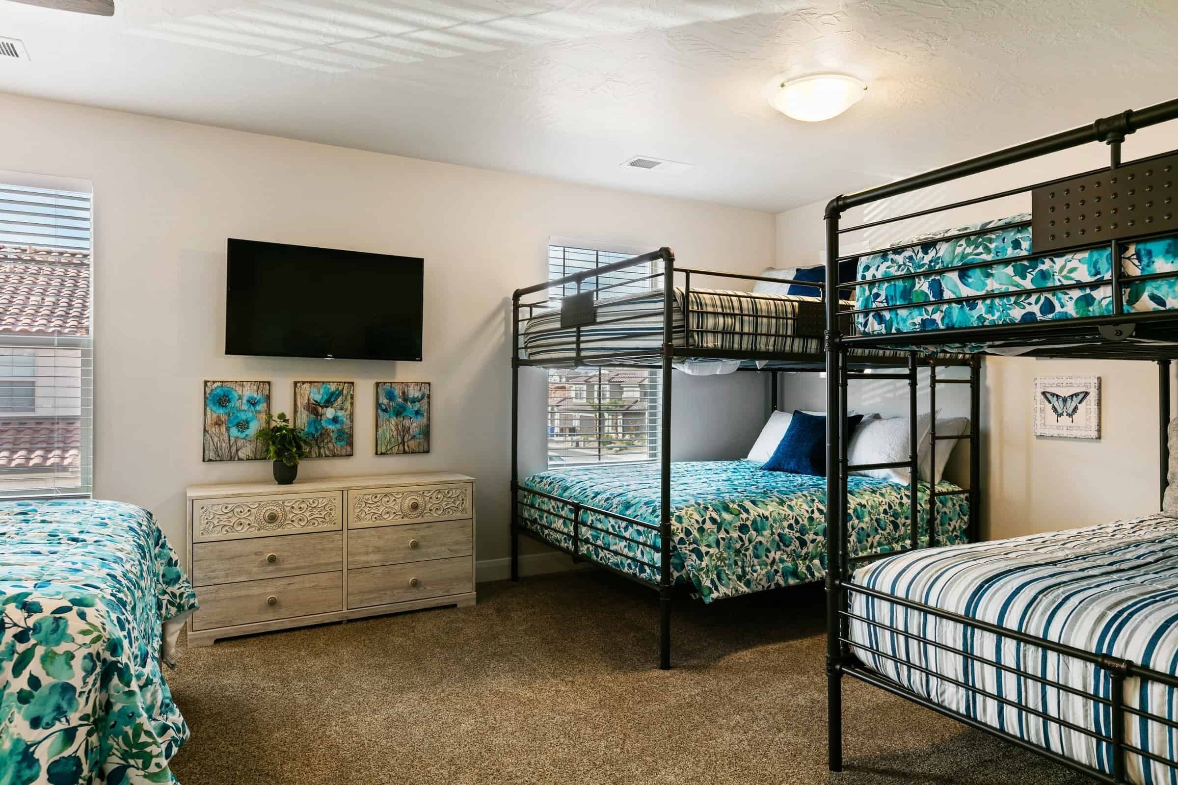 A bunk bed room with a television, dresser, and artwork on the wall.