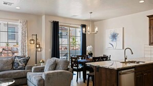 A modern kitchen with a central island, dining area with chairs, and a sofa. - Libelle Landing by RedAwning (Washington)
