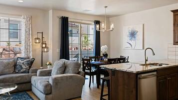 A modern kitchen with a central island, dining area with chairs, and a sofa.