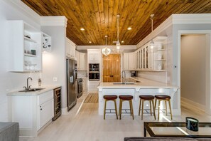 A modern kitchen with white cabinetry, a wooden ceiling, and a central island with stools. - The Meadows-Mallory Square North |Community Pool |Mins to Gulf Beaches |Gourmet Kitchen |Boat Dock (Pensacola)