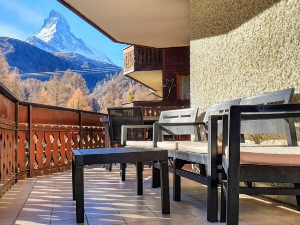 A balcony with a view of a mountain, furnished with a table and chairs. - Nirwana by Interhome (Zermatt)