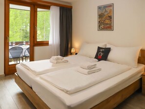 A hotel room with a double bed, a painting on the wall, and a view of the outdoors through a window. - Nirwana by Interhome (Zermatt)