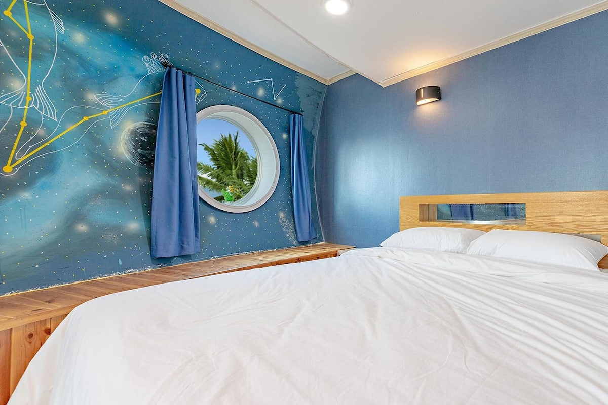 Une chambre à coucher avec un lit, un miroir rond et une fresque murale.