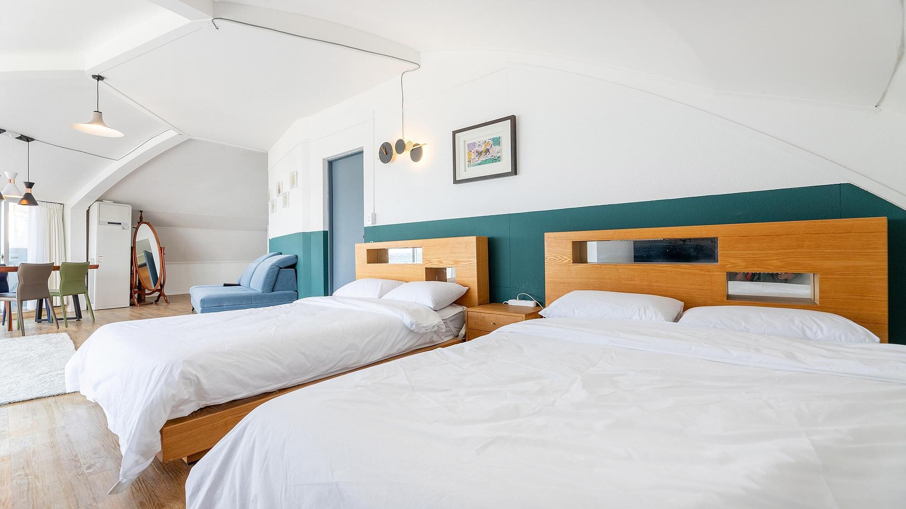 A modern hotel room with two single beds, a desk, and a chair.