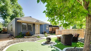 Una casa con un giardino retrostante, che include un putting green, mobili da esterno e una recinzione in legno.