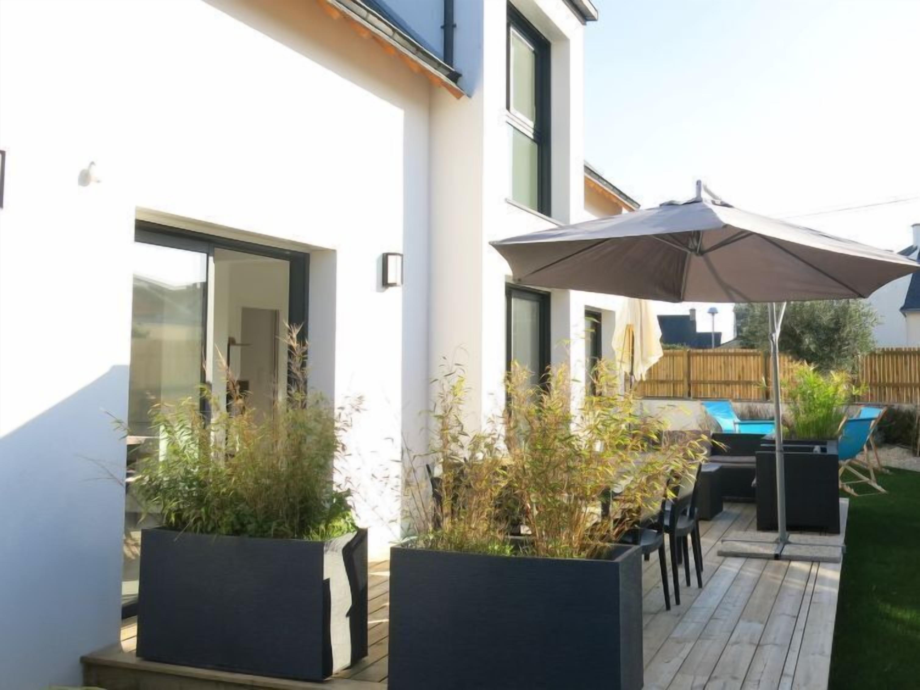 A modern patio with outdoor seating, a pool, and a large umbrella.