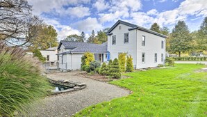 Une maison à deux étages avec une pelouse bien entretenue et un petit étang.