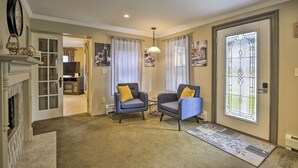 Un salon avec deux fauteuils, une cheminée et une porte en vitrail.