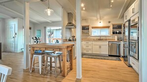 Un'ampia cucina con mobili bianchi, elettrodomestici in acciaio inossidabile e un'area pranzo in legno.