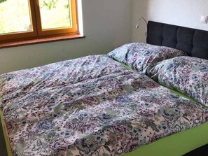 Un letto con biancheria da fiori, una finestra con vista e un lampadario a parete.