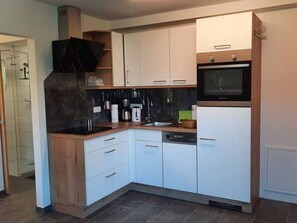 Una cucina moderna con mobili bianchi, un piano di lavoro nero e un forno integrato.
