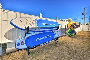 Una balsa inflable azul y blanca con el texto "MAXKARE" sobre ella, ubicada en una zona cubierta de césped junto a una cerca blanca.