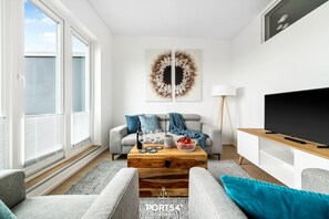 A modern living room with a sofa, coffee table, and TV stand. - OstseeOase - Infrared Sauna, Shower, Fireplace, Rooftop Terrace, Parking Space (Olpenitz)
