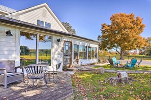 Ein Haus mit einer Veranda, Sitzgelegenheiten im Freien und einem großen Baum.