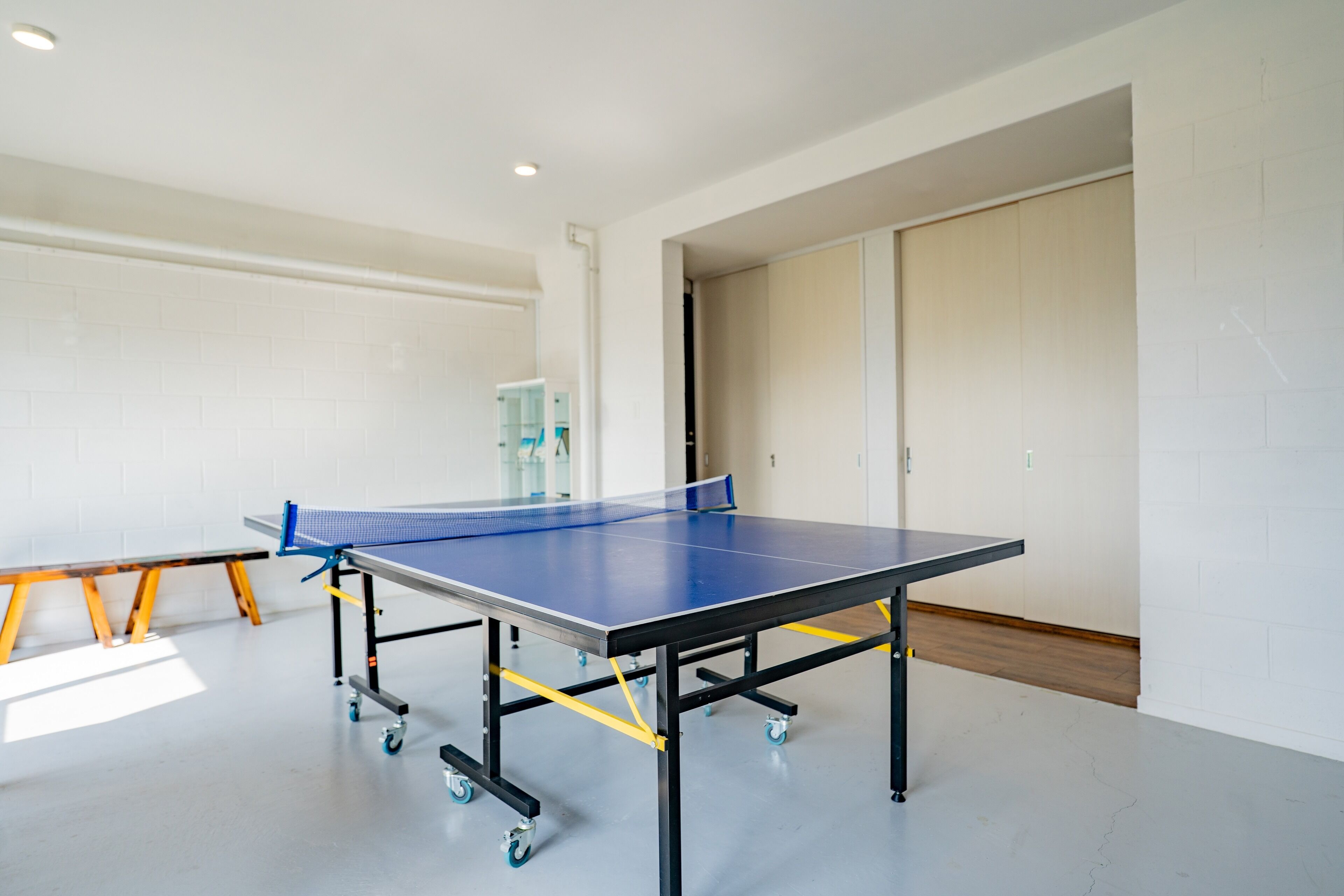 Une table de ping-pong dans une pièce aux murs blancs et au plancher en bois.