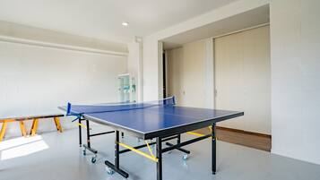 Une table de ping-pong dans une pièce aux murs blancs et au plancher en bois.