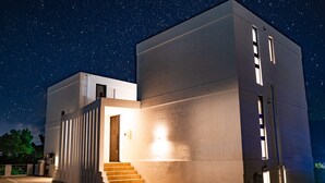 A modern building with a staircase leading to a door, under a starry night sky. - Sea Space Road (Onna)