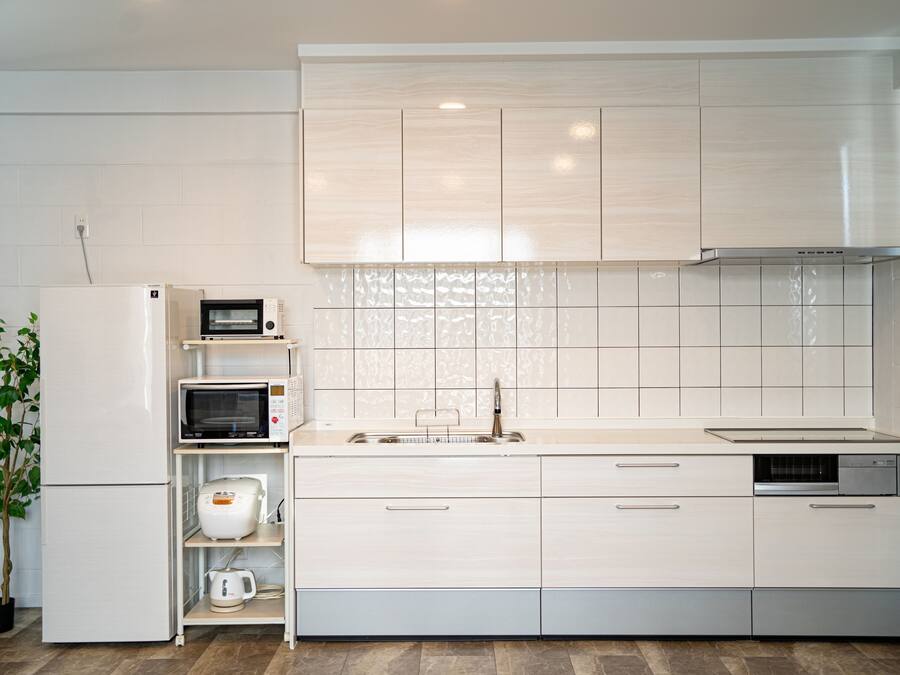 A modern kitchen with white cabinetry, a built-in microwave, a coffee maker, and a dishwasher.