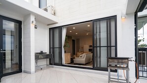 A modern interior with a glass door leading to a living area, a small table, and a water dispenser. - Sea Space Road (Onna)