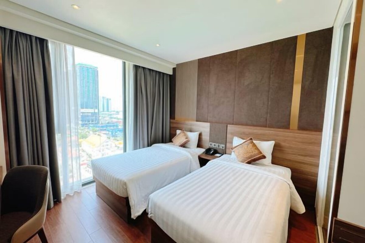 A hotel room with two beds, a desk, and a chair.