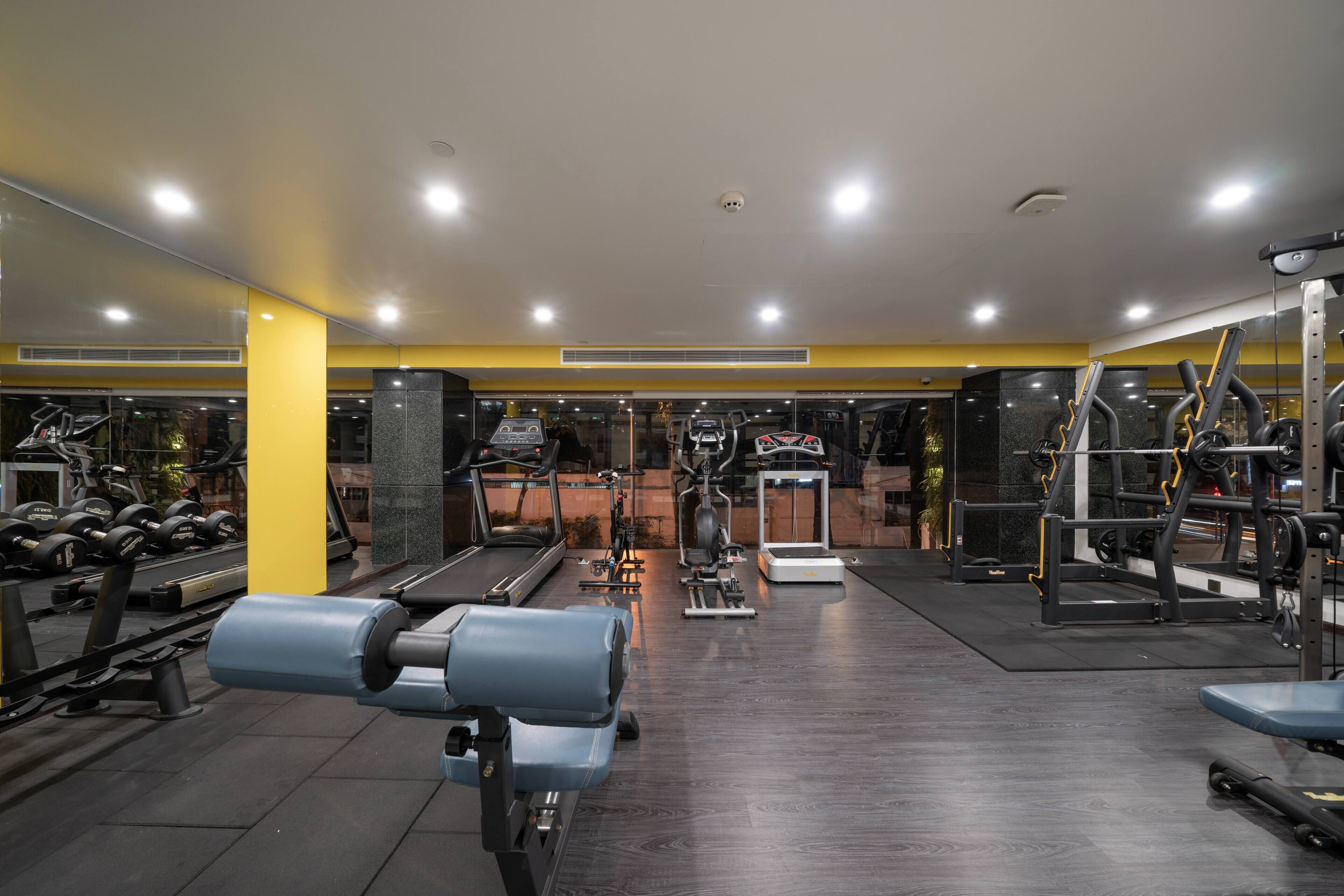Et fitnesscenter med løbebånd, styrkemaskiner og håndvægte.