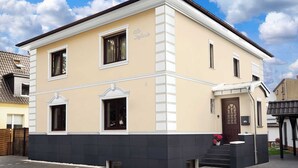 Kaksikerroksinen rakennus, jonka julkisivu on beigen värinen, siinä on valkoiset koristeet ja tumma pohja. Sisäänkäynnin yläpuolella on kyltti, jossa lukee: ”Villa Santinelli”.
