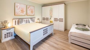 A bedroom with a bed, bedside tables, a wardrobe, and artwork on the wall. - Ahlbeck Villa Stephanie Bungalow H2AS rear - Ahlbeck Villa Stephanie (Heringsdorf)