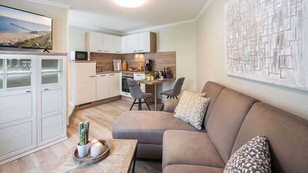 A modern living room with a sofa, a coffee table with decorative items, and a TV mounted on a cabinet. - Ahlbeck Villa Stephanie Bungalow H2AS rear - Ahlbeck Villa Stephanie (Heringsdorf)