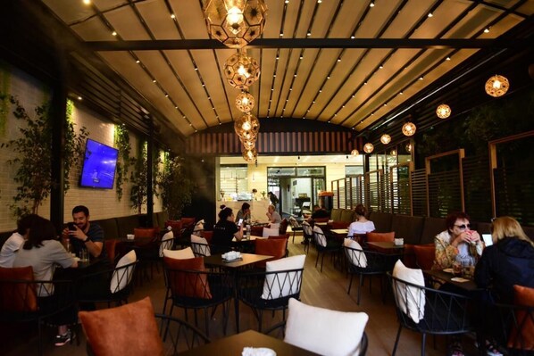 Um restaurante com decoração moderna, apresentando diversos tipos de assentos e uma área de refeições central.