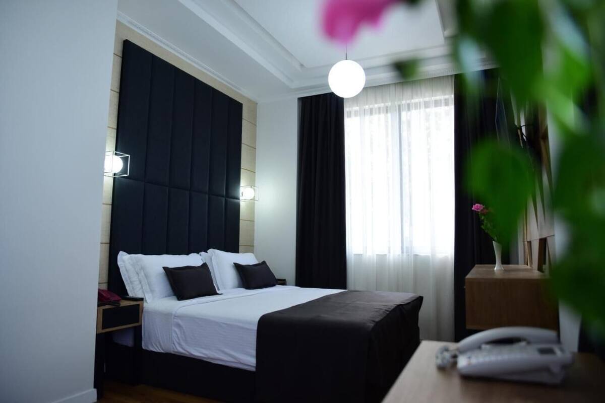 A hotel room with a bed, bedside tables, a lamp, and a telephone.