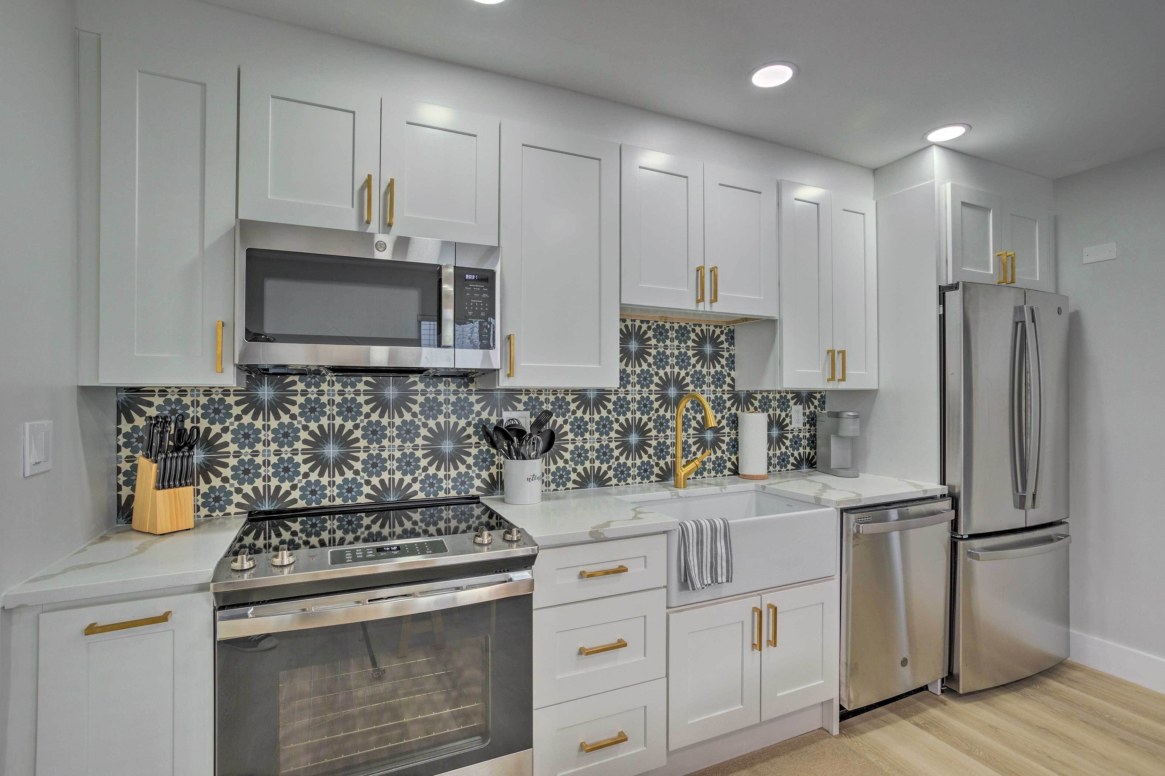 A modern kitchen with white cabinets, stainless steel appliances, and a patterned backsplash.