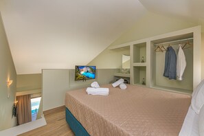 A bedroom with a bed, a TV, a wardrobe, and a view of the outdoors.