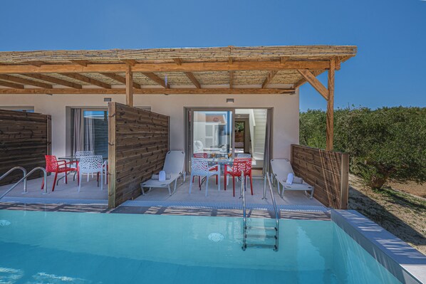 Ein Poolbereich mit einer Holz-Pergola, Sitzgelegenheiten im Freien und Blick auf die umliegende Landschaft.