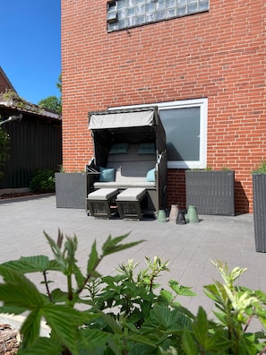 En terrasse med indbygget siddeplads, et vindue og krukker med planter.