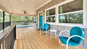 A covered porch with wooden flooring, teal chairs, a small table, and a teal door. - Brazos River Bungalow - Close To Silos & Baylor (Waco)